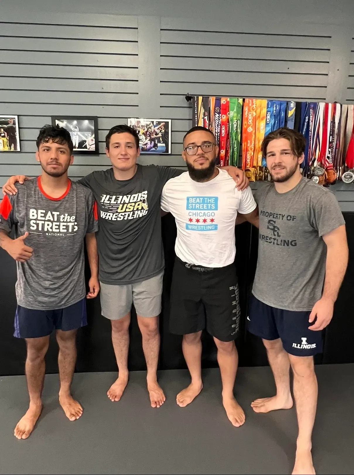 Coach Nick Spacek with three wrestlers in Beat the Streets and Illinois USA Wrestling shirts at Apex